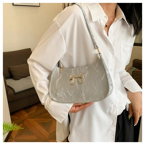 Silver shoulder bag with pleated texture and metal butterfly detail on model