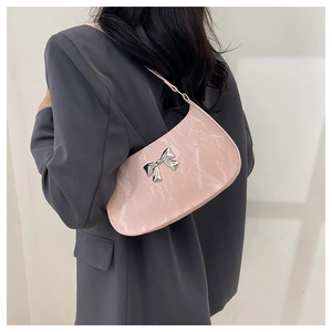 Shoulder view of a pink marble texture crescent bag with a silver metal bow detail