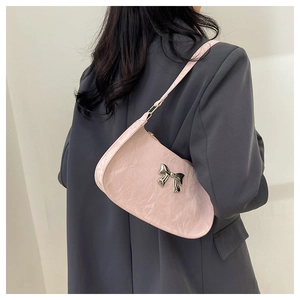 Close-up of pink patent leather underarm bag featuring a silver metal bow decoration