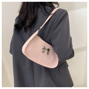 Detailed view of pink wrinkled patent leather shoulder bag with a silver metal bow