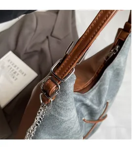 Vista dettagliata della borsa a tracolla in denim grigio con cinturino in pelle marrone
