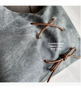 Dettaglio macro del tessuto denim grigio lavato con laccio in pelle marrone e occhiello