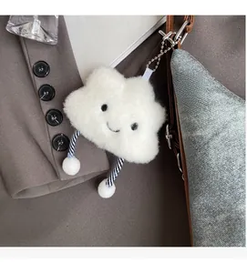 Dettaglio di un ciondolo a nuvola in peluche bianco appeso a una borsa blu testurizzata