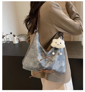 Dettaglio borsa tote in denim lavato con laccetti in pelle marrone e ciondolo a nuvola