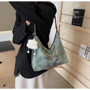 Dettaglio di una borsa tote verde vintage con tracolla in pelle e ciondolo nuvola