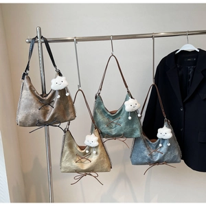 Dettaglio di borse tote in ecopelle vintage con allacciatura incrociata e ciondolo morbido