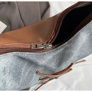 Dettaglio della borsa tote in denim e pelle con cerniera e occhielli metallici rifiniti