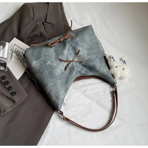 Dettaglio borsa tote in denim grigio con fiocchi marroni e ciondolo a nuvola
