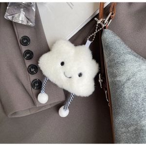 Dettaglio portachiavi a nuvola di peluche bianco con sorriso su borsa in tela grigia