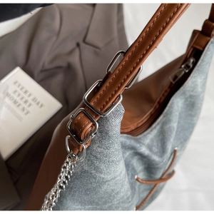 Dettaglio della borsa tote in denim con spalline in pelle e fibbia argento