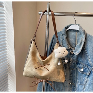 Dettaglio della borsa tote in pelle scamosciata marrone con lacci e catena