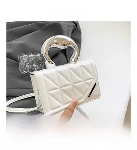 Detail of white quilted bag featuring a unique liquid silver metal curved handle