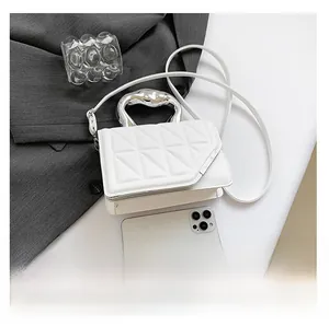 Detail of white quilted crossbody bag featuring a unique silver metallic handle and leather