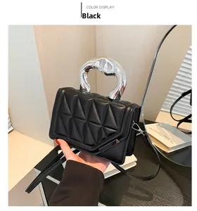 Detail of black quilted shoulder bag with unique silver metal handle and sleek PU texture