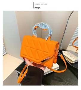 Detail of orange quilted handbag with silver liquid metal handle and adjustable strap