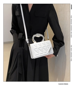 Detailed view of white quilted crossbody bag with silver curved handle and slim shoulder strap