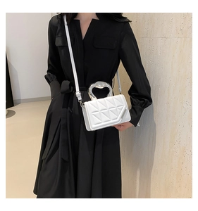 Detail view of white quilted crossbody bag with unique irregular silver metal handle