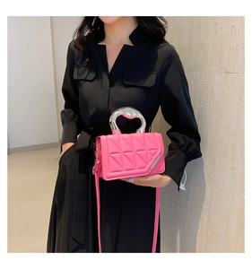 Close-up of pink quilted crossbody bag with stylish silver heart handle and leather chain