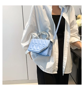 Close-up of light blue quilted crossbody bag featuring a sleek silver metal circular handle