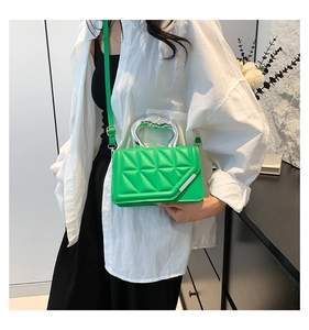 Detail of green quilted handbag featuring a sculptural silver handle and chic leather strap