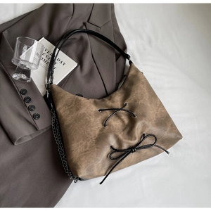 Dettaglio borsa tote in pelle lavata marrone retrò con fiocco intrecciato e catena