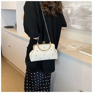 Detail of a vintage cream leather shell bag with gold heart studs and kiss-lock closure