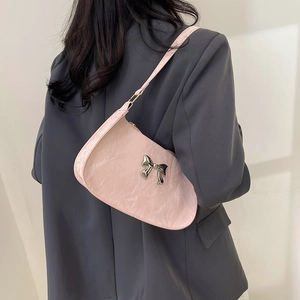 Pink glossy wrinkled underarm bag with silver bow shown on model's shoulder