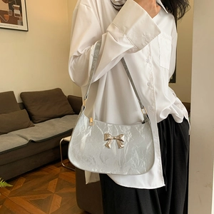 Silver crescent underarm bag with glossy pleated texture and metal bow decoration