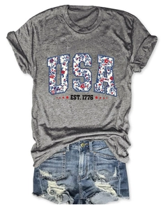 Detail of USA EST 1776 floral print on grey T-shirt paired with frayed denim shorts