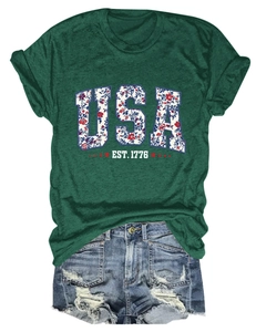 Close-up of USA EST. 1776 floral letters on dark green t-shirt with ripped denim shorts