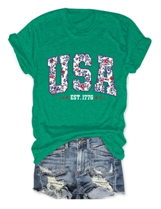 Close-up of green USA EST. 1776 floral print T-shirt with distressed denim shorts