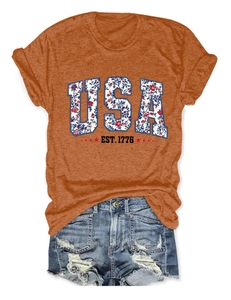 Flat lay showing details of the floral USA print and red stars on the orange cotton t-shirt