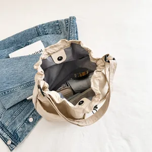 Detalle de bolso tipo cubo de nailon beige mostrando espacio para objetos diarios