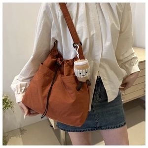 Detail of caramel nylon bucket bag with drawstring closure and cute plush cup charm