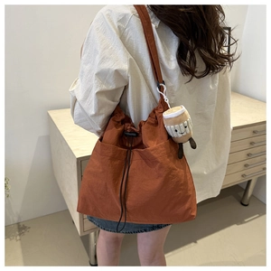 Bolso de nailon caramelo con cierre de cordón y accesorio de peluche de taza de café