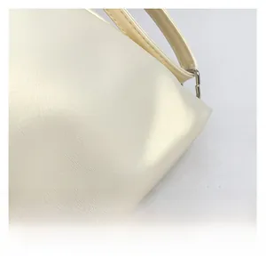 Close-up of creamy white faux leather tote bag showing fine texture and silver metal rings