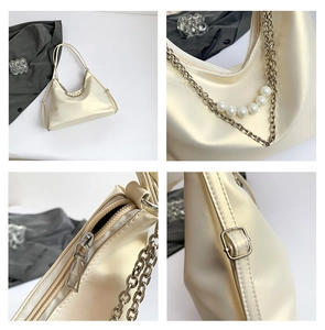 Detail view of cream shoulder bag featuring pearl chain accents and adjustable buckle
