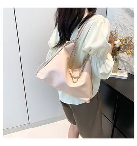 Detail view of stylish beige leather tote bag with elegant pearl and chain strap