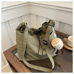 Detail of olive green nylon tote bag with drawstring closure and plush cup pendant