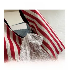 Detail shot of a red and white striped tote with delicate white lace bow and canvas texture