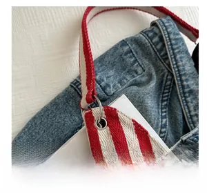 Detail of red and white striped canvas strap with silver ring buckle on a fashion bucket bag