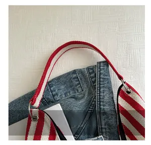 Close-up of red and white striped canvas handles on a dark blue denim bucket bag