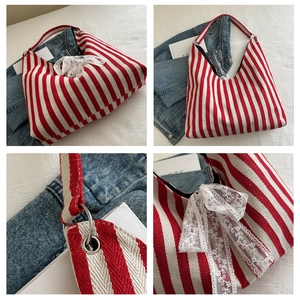 Detail of red and white striped canvas tote bag with white lace bow and silver rings