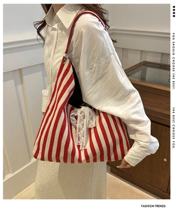 Detail of red striped canvas tote bag with a white lace bow decoration for casual fashion