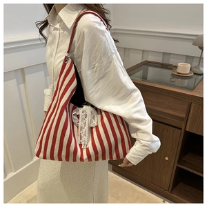 Close-up of a striped canvas tote bag featuring a delicate white lace bow detail