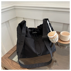 Detail of black nylon tote bag with drawstring closure and adjustable shoulder strap