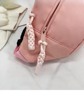 Gros plan d'une fermeture éclair rose avec tirette en corde bicolore sur un sac poitrine