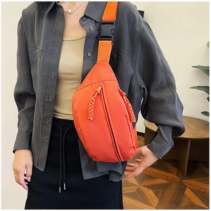 Détail du sac de poitrine en nylon imperméable orange vif avec large sangle et boucle