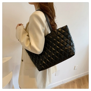 Quilted black nylon tote bag shown on model with classic diamond stitch pattern