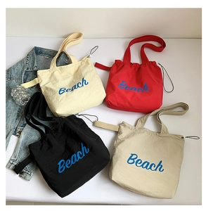 Detail of colorful nylon beach tote bags with drawstring closure and letter prints